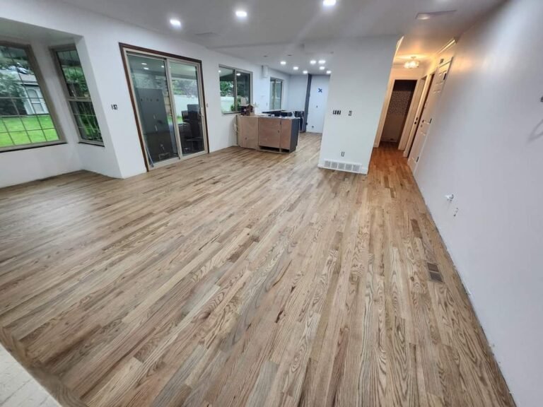 Newly installed light oak hardwood flooring in a spacious, open-concept home under renovation.