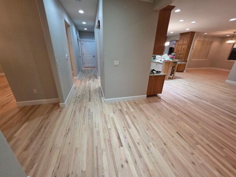 Natural light-colored hardwood floors in an open-concept home interior with grey walls.