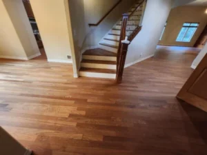 Polished medium-toned hardwood flooring in a home entryway leading to a wooden staircase.